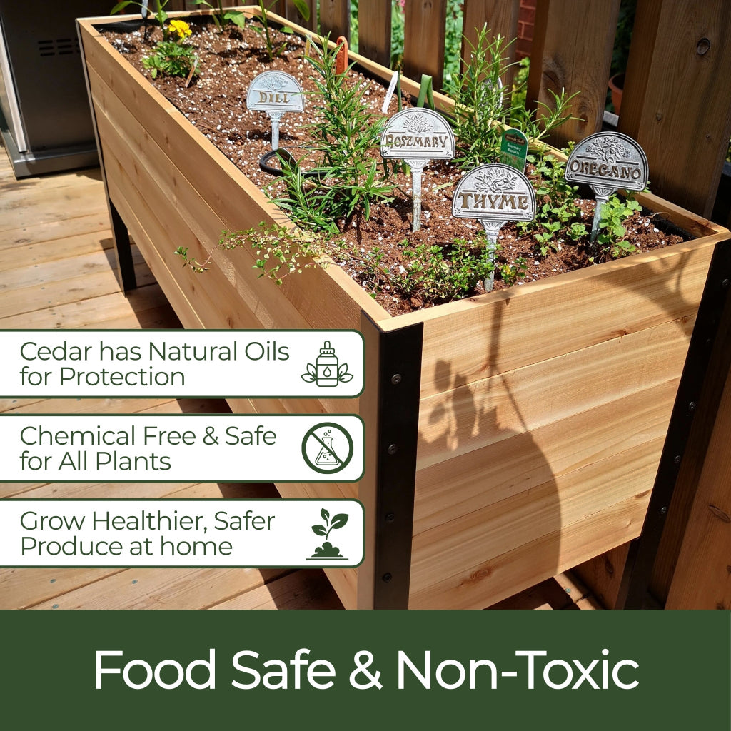 Wooden planter box with plants and labels, on a wooden deck.